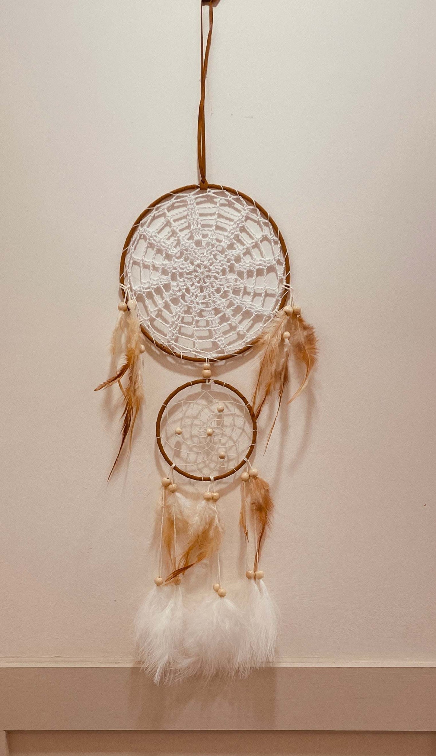 Indian style handcrafted multi-ring dreamcatcher with beige and white feathers, intricate weaving, and cultural decor elements.