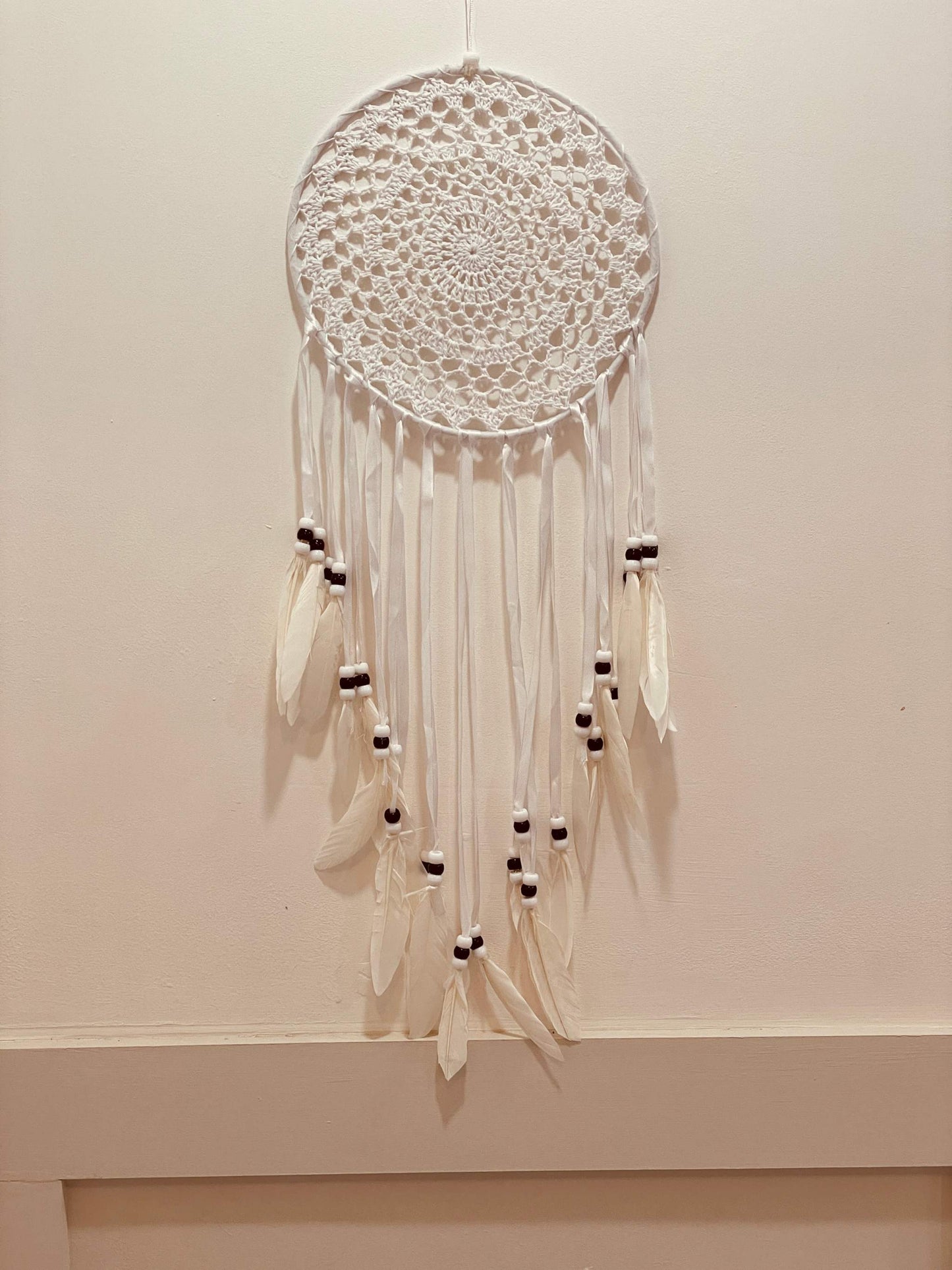 Indian style multi-ring dreamcatcher with intricate design and beads hanging on a wall.
