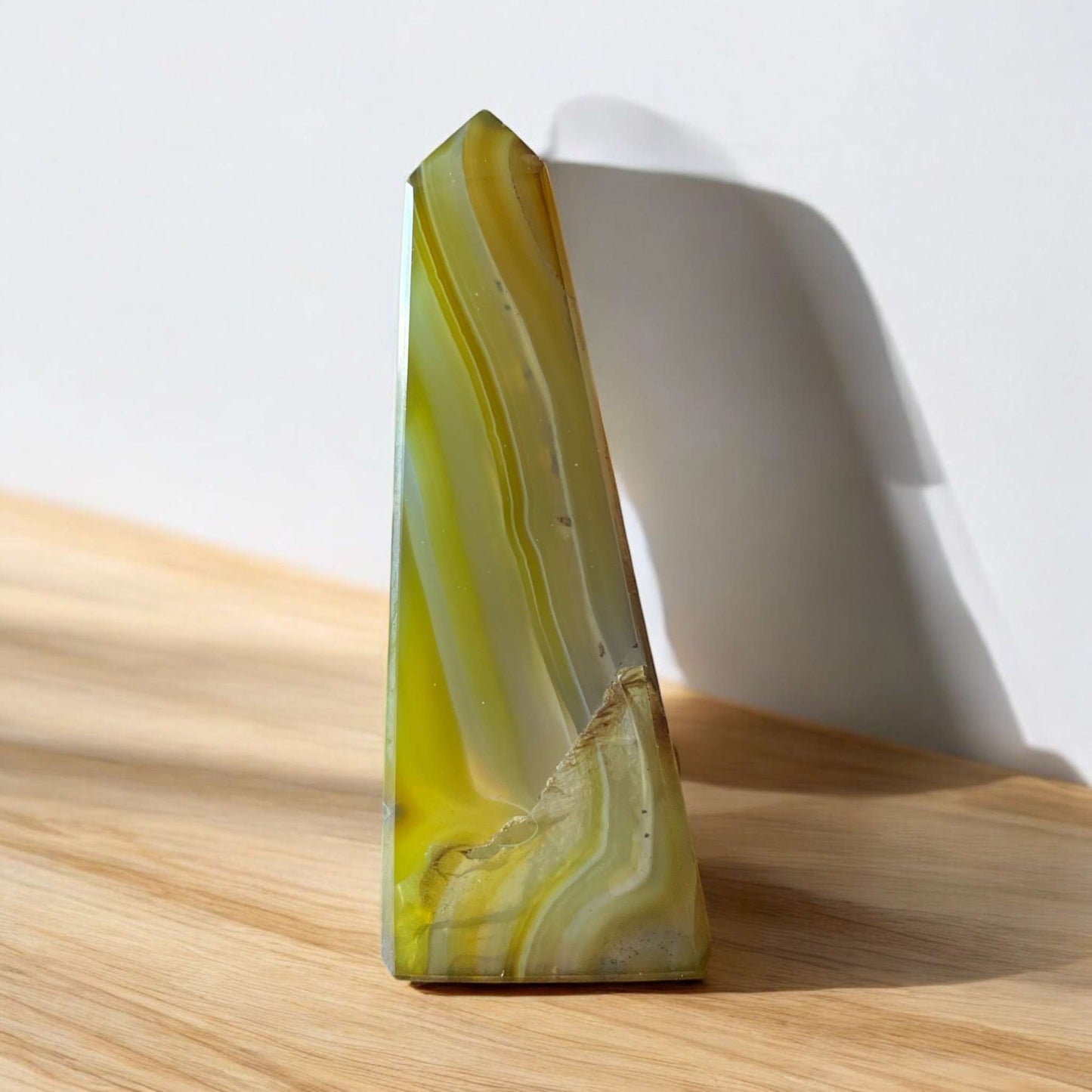 Agate Obelisk on wood surface, 85mm tall, with natural banding and earthy tones, ideal for emotional balance and protection.