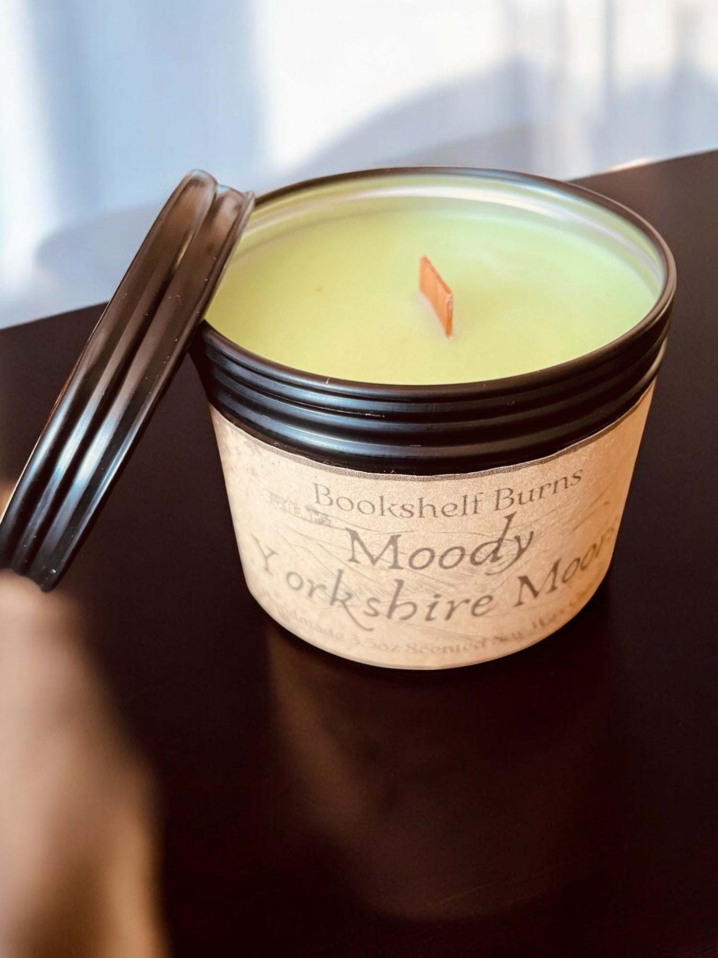 Hand-poured scented candle in a tin container with wooden wick.