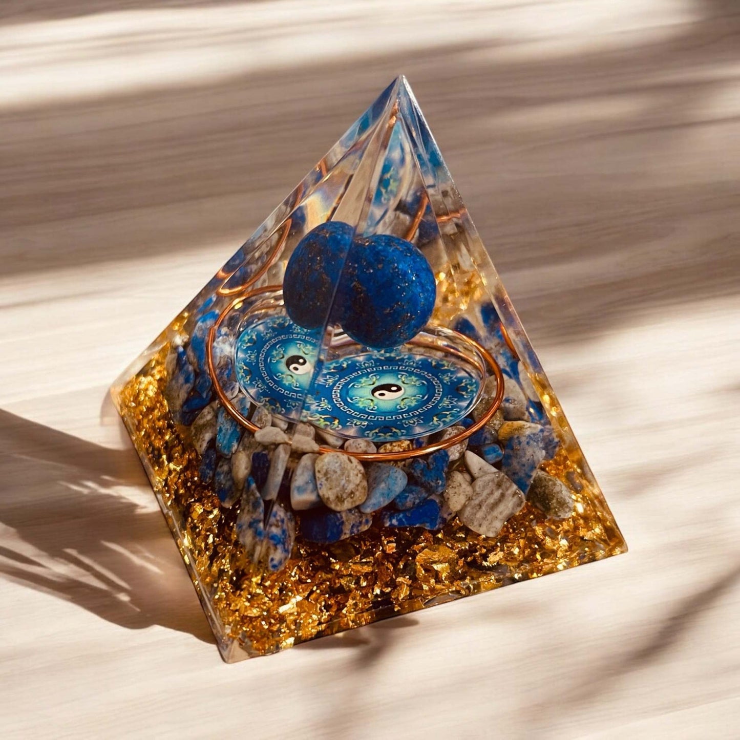Orgonite Pyramid with gold and blue accents, promotes positive energy and balance.