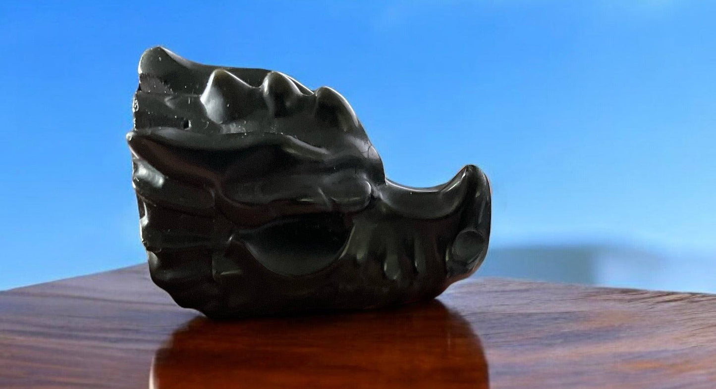 Carved gemstone dragon head in black obsidian on display.