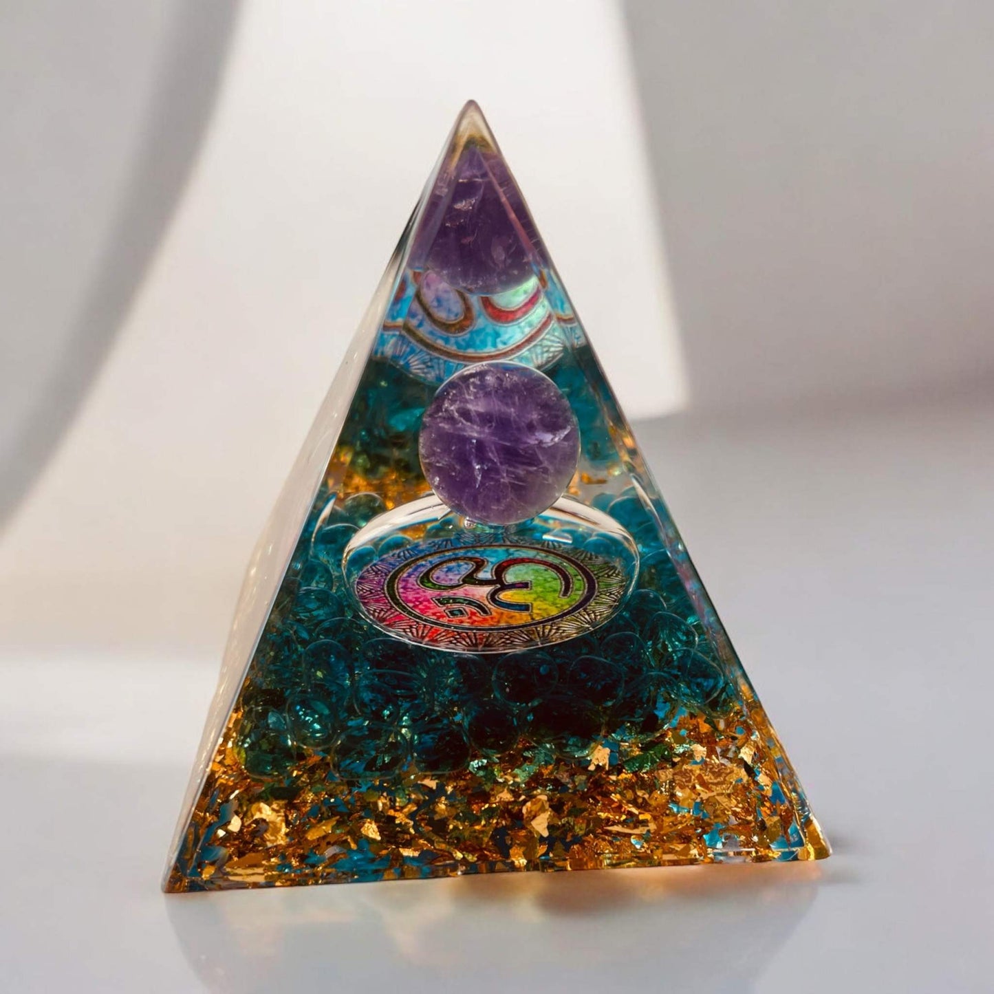 Colourful Orgonite Pyramid for energy balance and stress reduction in meditation spaces.